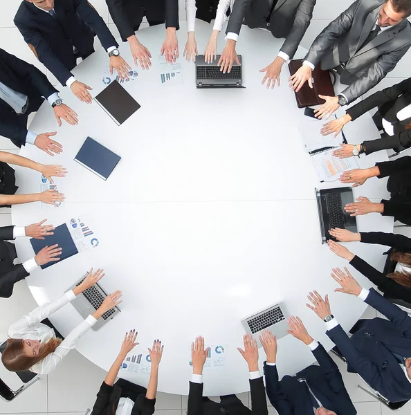 Grupo de empresarios sentados en la mesa redonda, y poniendo sus palmas sobre la mesa —  Fotos de Stock