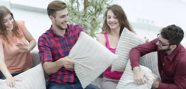 Fröhliche Freunde spielen Kissenschlacht, sitzen auf der Couch — Stockfoto