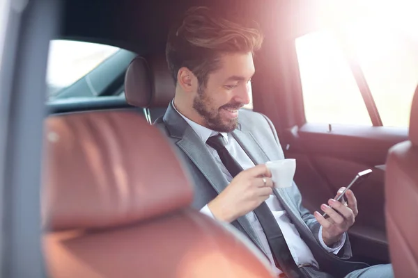 Felice giovane uomo d'affari utilizzando il telefono cellulare nel sedile posteriore della macchina — Foto Stock