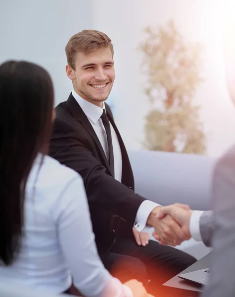 Due giovani uomini felici che si stringono la mano mentre si siedono in ufficio — Foto Stock