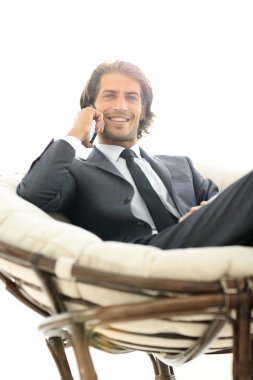 iş adamı rahat bir sandalyede otururken Smartphone'da konuşuyor.