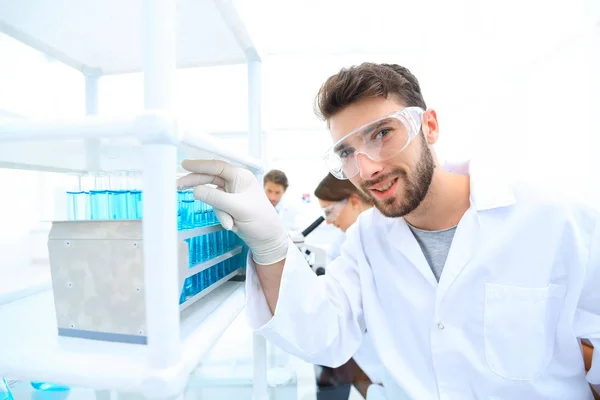 En ung man som gör ett experiment i ett kemiskt laboratorium — Stockfoto