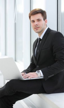 Genç profesyonel ofis pencere arka plan üzerinde dizüstü bilgisayar ile