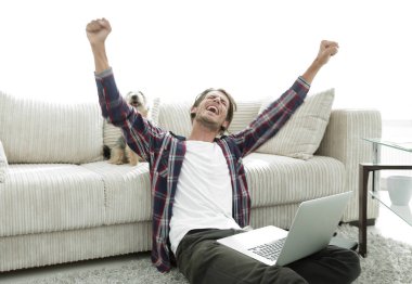 mutlu genç adam köpeğiyle oturma odasında exults