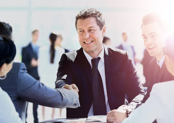 Homem de negócios maduro apertando as mãos para selar um acordo com seu parceiro e colegas em um escritório moderno — Fotografia de Stock