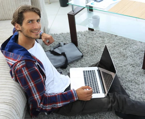 Biznes facet z laptopa siedząc na dywanie w salonie. — Zdjęcie stockowe