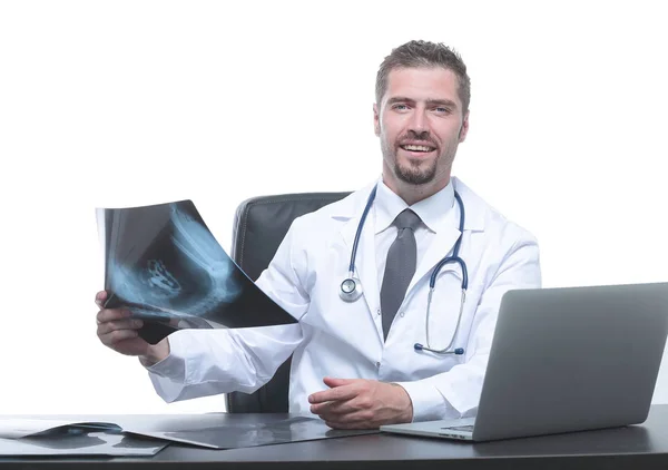 Лікар оглядає рентгенівський знімок, сидячи за столом — стокове фото