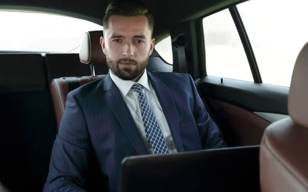 Hombre de negocios con portátil sentado en un coche cómodo — Foto de Stock