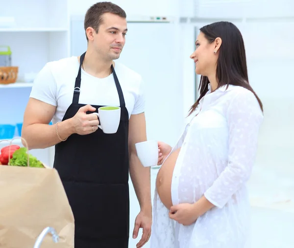 Husband and his pregnant wife with a Cup of cocoa standing in the kitchen. — Stock Photo, Image