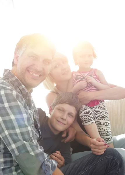 Gezin met twee kinderen elkaar zitten en kijken naar camera — Stockfoto