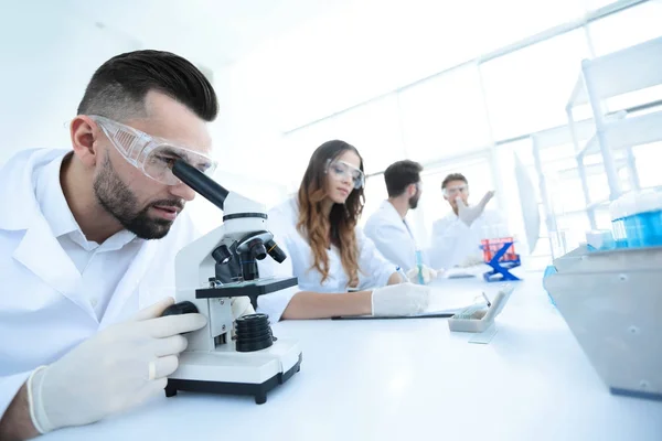 Técnico de laboratorio masculino que mira muestras en el microscopio — Foto de Stock