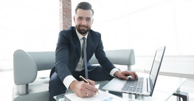 İş grafikleri ile bir dizüstü bilgisayar üzerinde çalışan iş adamı