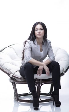 Genç kadın bir yuvarlak rahat yumuşak büyük sandalyede oturuyor.