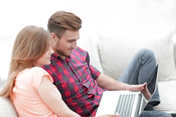 Νεαρός άνδρας και κορίτσι με φορητό υπολογιστή κάθεται στον καναπέ — Φωτογραφία Αρχείου