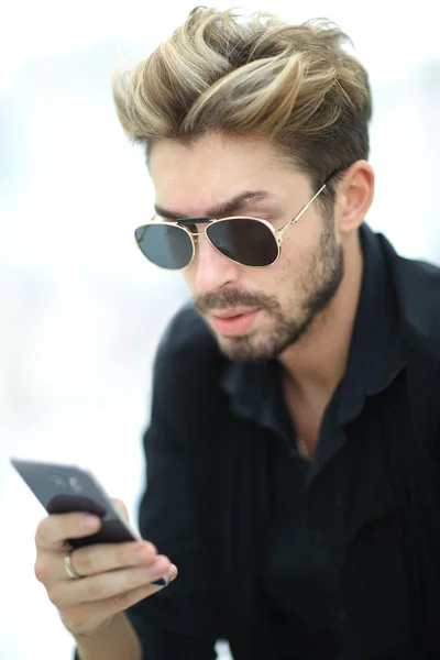 Стильный бородатый самец сидит и использует смартфон . — стоковое фото
