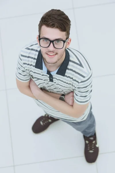 Blick von oben auf einen fröhlichen jungen Mann in Casualtracht, der die Arme kreuzt — Stockfoto