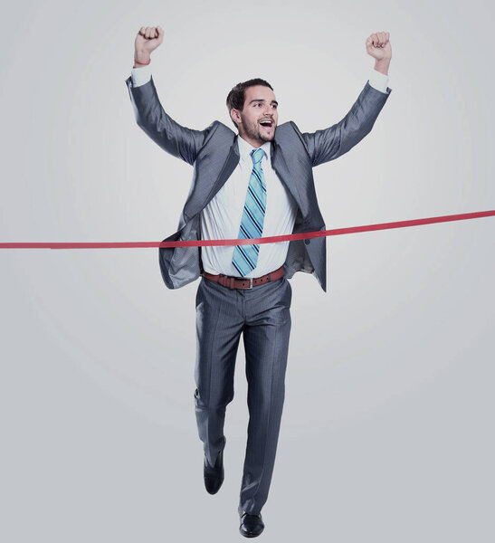 Happy businessman running through finishing line. Isolated on white