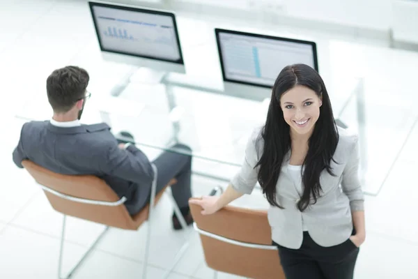 Mujer de negocios exitosa de pie cerca del lugar de trabajo moderno —  Fotos de Stock