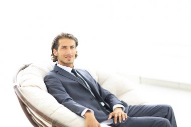 büyük rahat koltukta oturan genç işadamı.