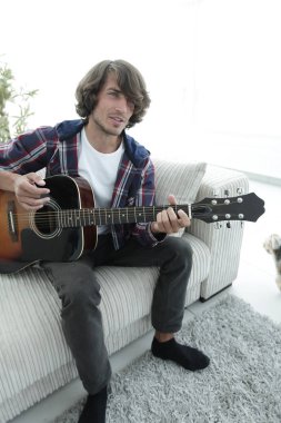 adam bir şarkı söyler ve kanepede oturan gitar çalar.