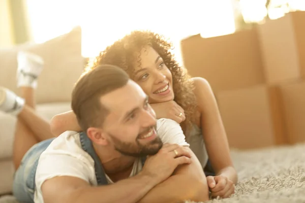 Pareja feliz acostada en la alfombra sobre el fondo borroso — Foto de Stock