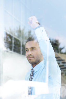 Camların arkasından manzara. Kendine güvenen iş adamı ofisinin penceresinden dışarı bakıyor.