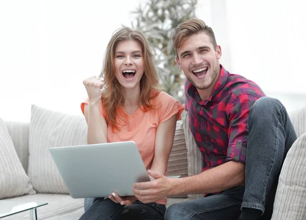 Jong koppel verheugt zich, zittend op de Bank tegenover de opengeklapte laptop — Stockfoto