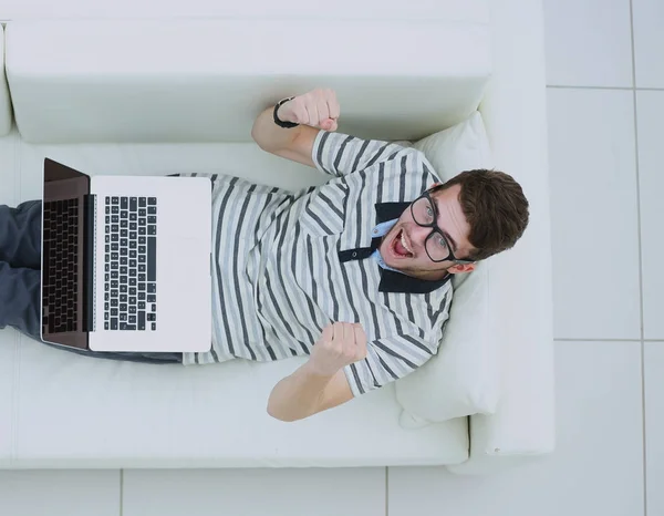 Aufgeregter junger Mann mit Laptop im hellen Wohnzimmer — Stockfoto