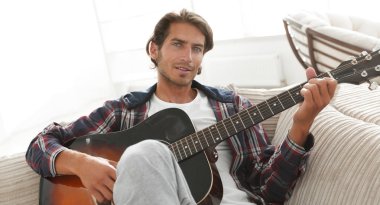 oturma odasında kanepede oturup gitar ile Modern adam.