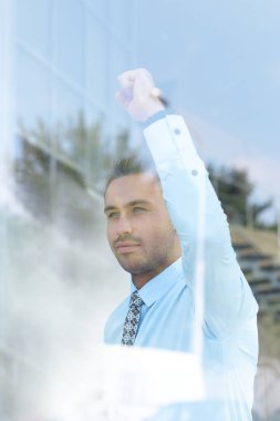 Camların arkasından manzara. Kendine güvenen iş adamı ofisinin penceresinden dışarı bakıyor.