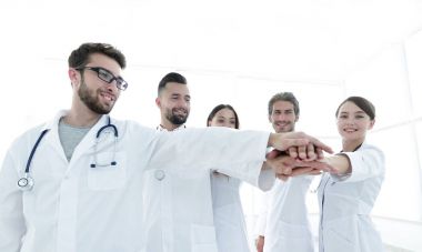 Doktorlar ve hemşireler tıbbi bir ekipte el ele tutuşuyorlar.
