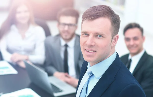 Jungunternehmer blickt auf den Hintergrund seines Teams in die Kamera — Stockfoto