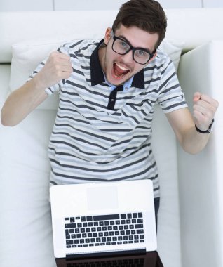 En baştan görüntüleyin. kanepede oturan dizüstü bilgisayar ile Skordan genç adam