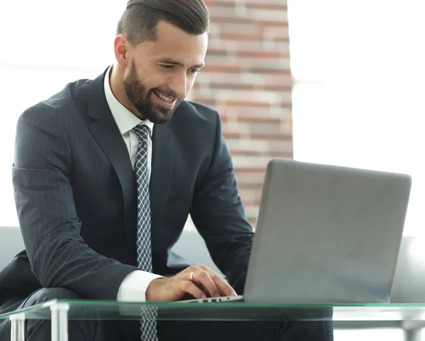 Zakenman die op laptop zittend op een bank in een kantoor werkt — Stockfoto