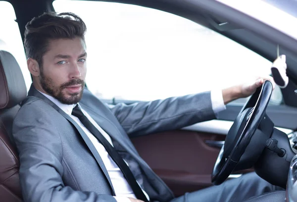 Hombre de negocios guapo en el asiento de los conductores en su coche — Foto de Stock