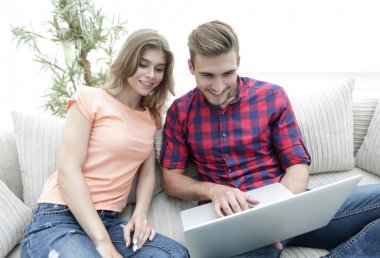 Mutlu modern çift internette sörf yapıyor ve evde dizüstü bilgisayarla çalışıyor.