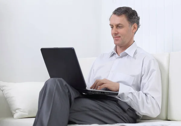 Успешный бизнесмен работает на ноутбуке, сидя на диване — стоковое фото