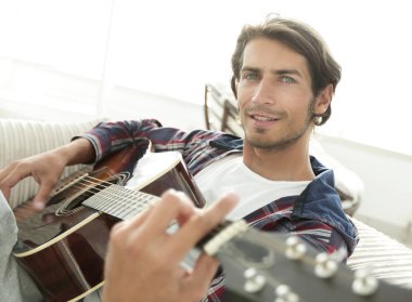 gitar oturma odasında kanepede oturan adam. bir yaşam tarzı kavramı