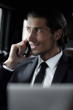 Telefonda konuşurken bir dizüstü bilgisayar ile arabasında işadamı