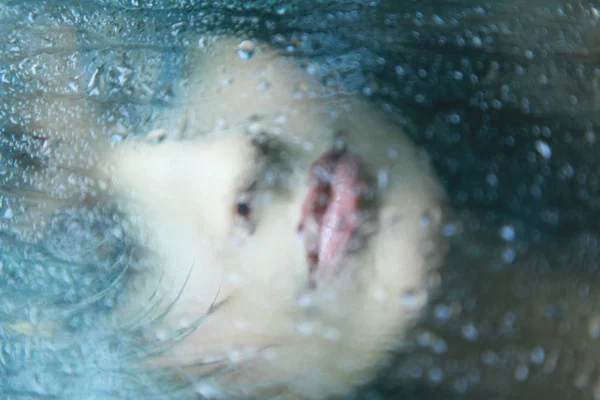 Belle femme regardant par la fenêtre le jour de pluie — Photo