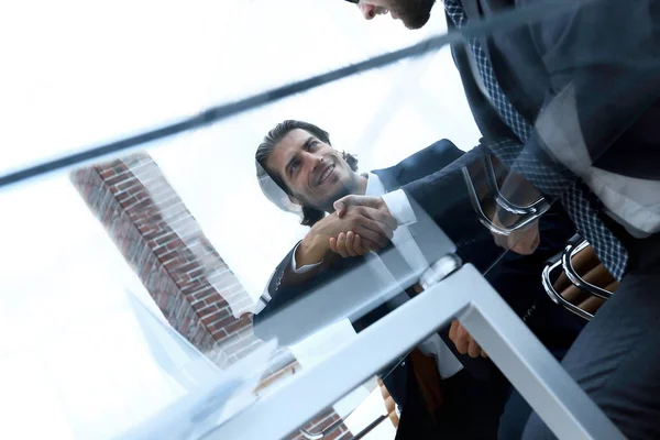 Handschlag kreativer Partner, der hinter einem Schreibtisch sitzt. — Stockfoto