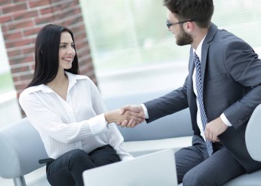 Yöneticisi ve müşteri ofis lobisinde otururken el sıkışma.