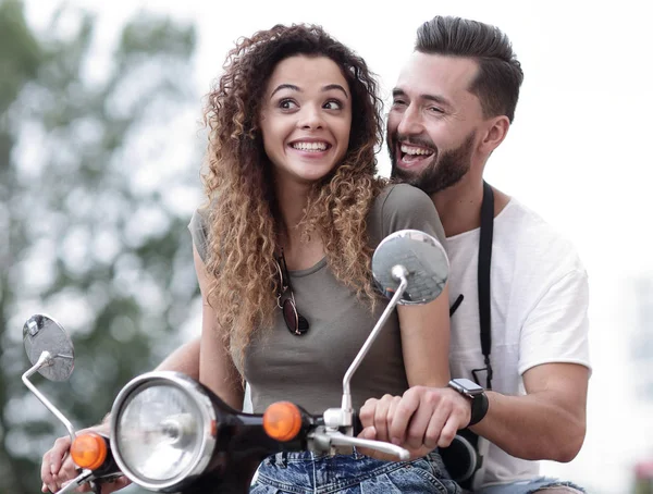 Attractive couple riding a scooter on a sunny day in the city — Stock Photo, Image