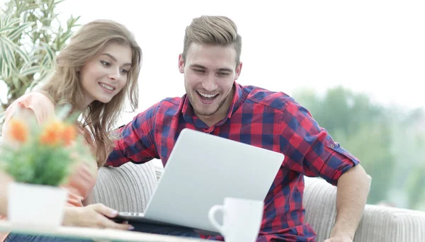 Glückliches junges Paar schaut einen Lieblingsfilm, während es in einem modernen Wohnzimmer sitzt. — Stockfoto