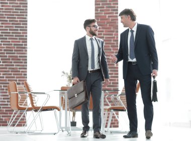 İki işadamları boyunca modern ofis binası içinde yürüyüş