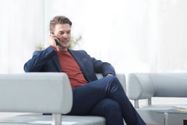 cep telefonu bir sandalyede oturup konuşurken işadamı.