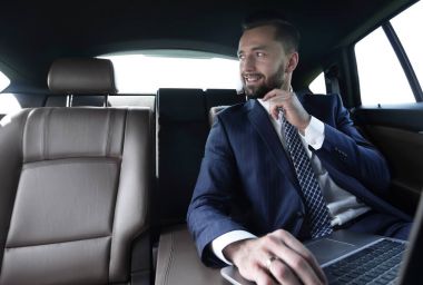 Arabanın içinde otururken kendine güvenen iş adamı