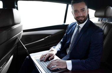 Arabanın içinde otururken dizüstü klavye üzerinde işadamı