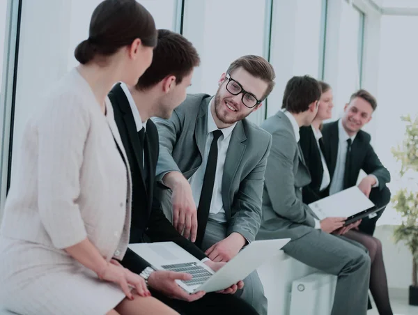 Colegas con el ordenador portátil y papeles sentarse y hablar en el vestíbulo befo — Foto de Stock