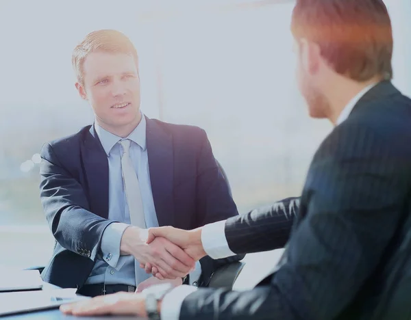 Affärskollegor som sitter vid ett bord under ett möte med två manliga chefer skakar hand — Stockfoto